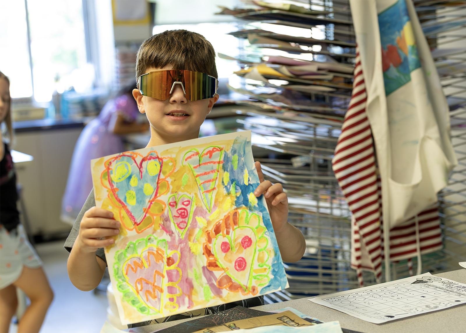 student wearing sunglasses holding up art work