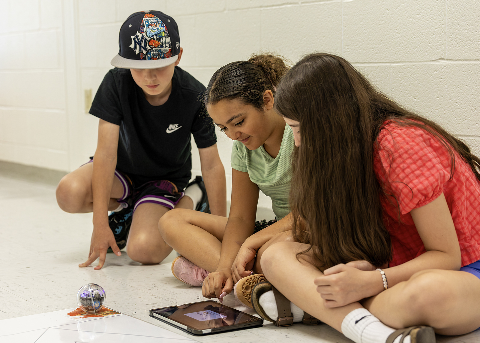 fifth graders coding a robot siting on the floor