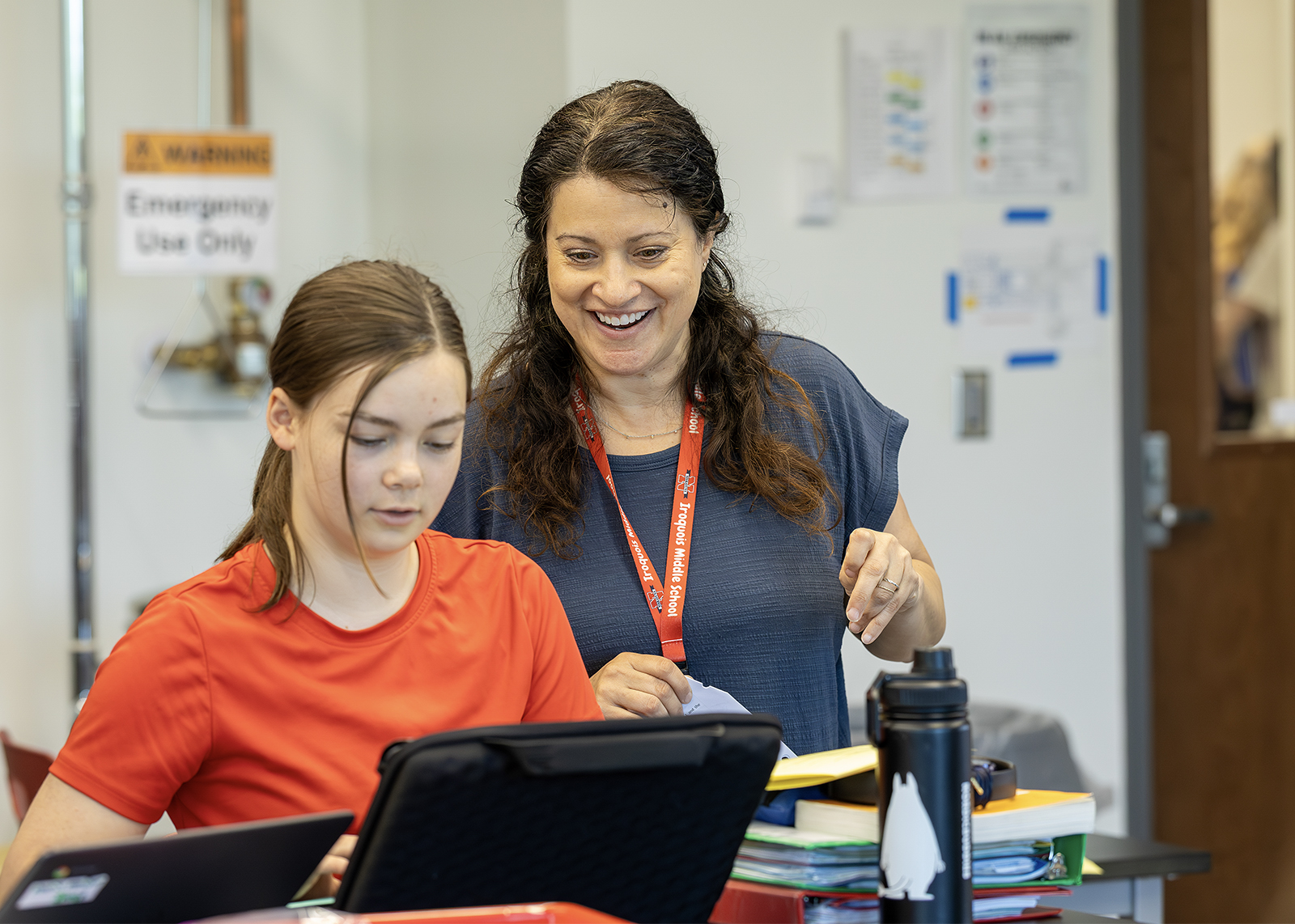 teacher smiling looking over student on computer
