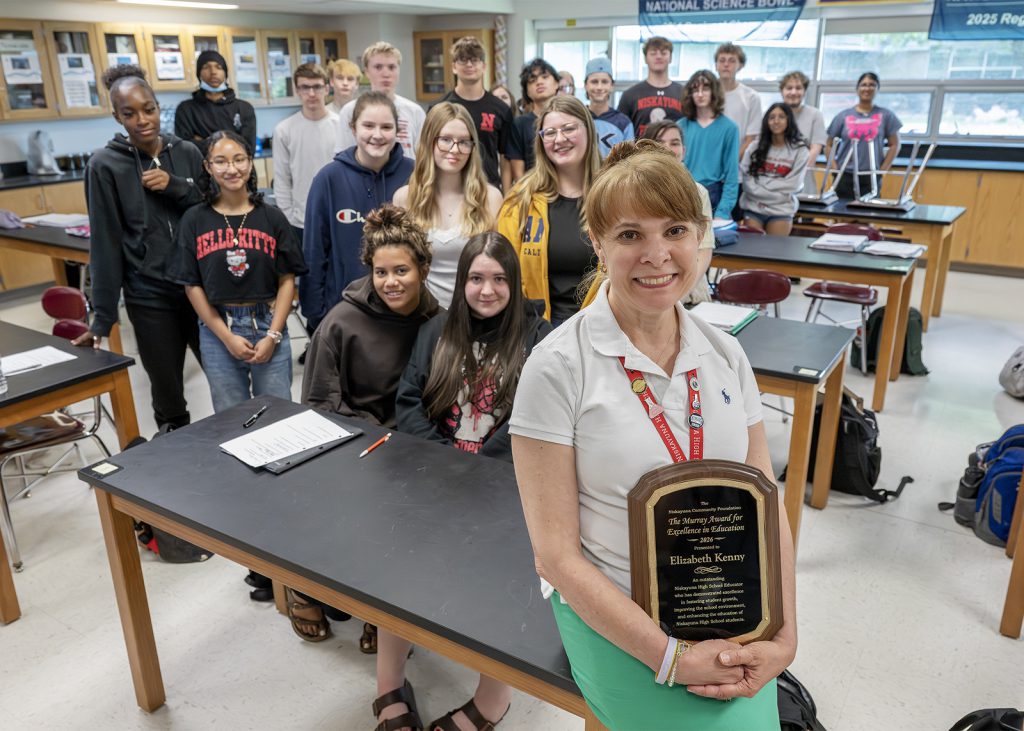 educator holding up Murray award plaque in front of classroom of kids