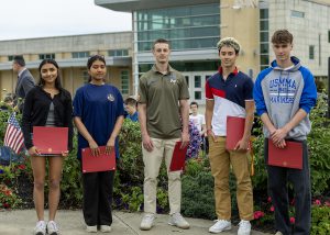 high school students with certificates smiling at military ceremony
