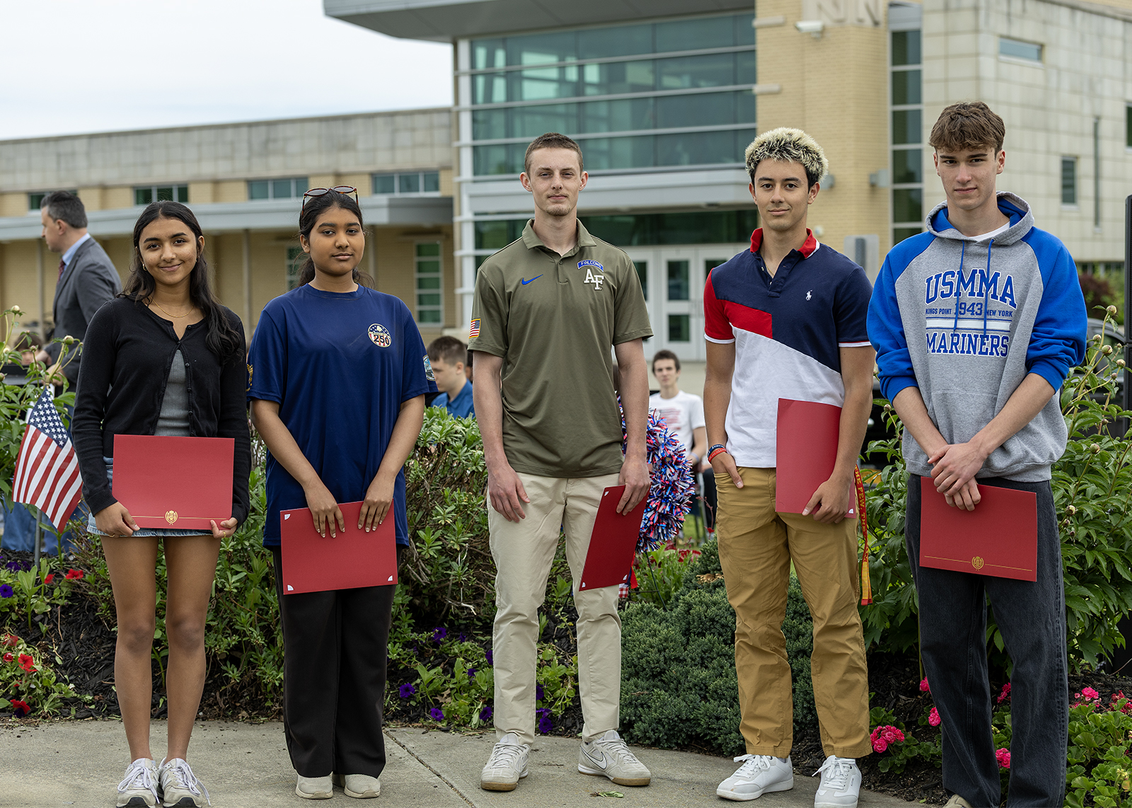 high school students with certificates smiling at military ceremony