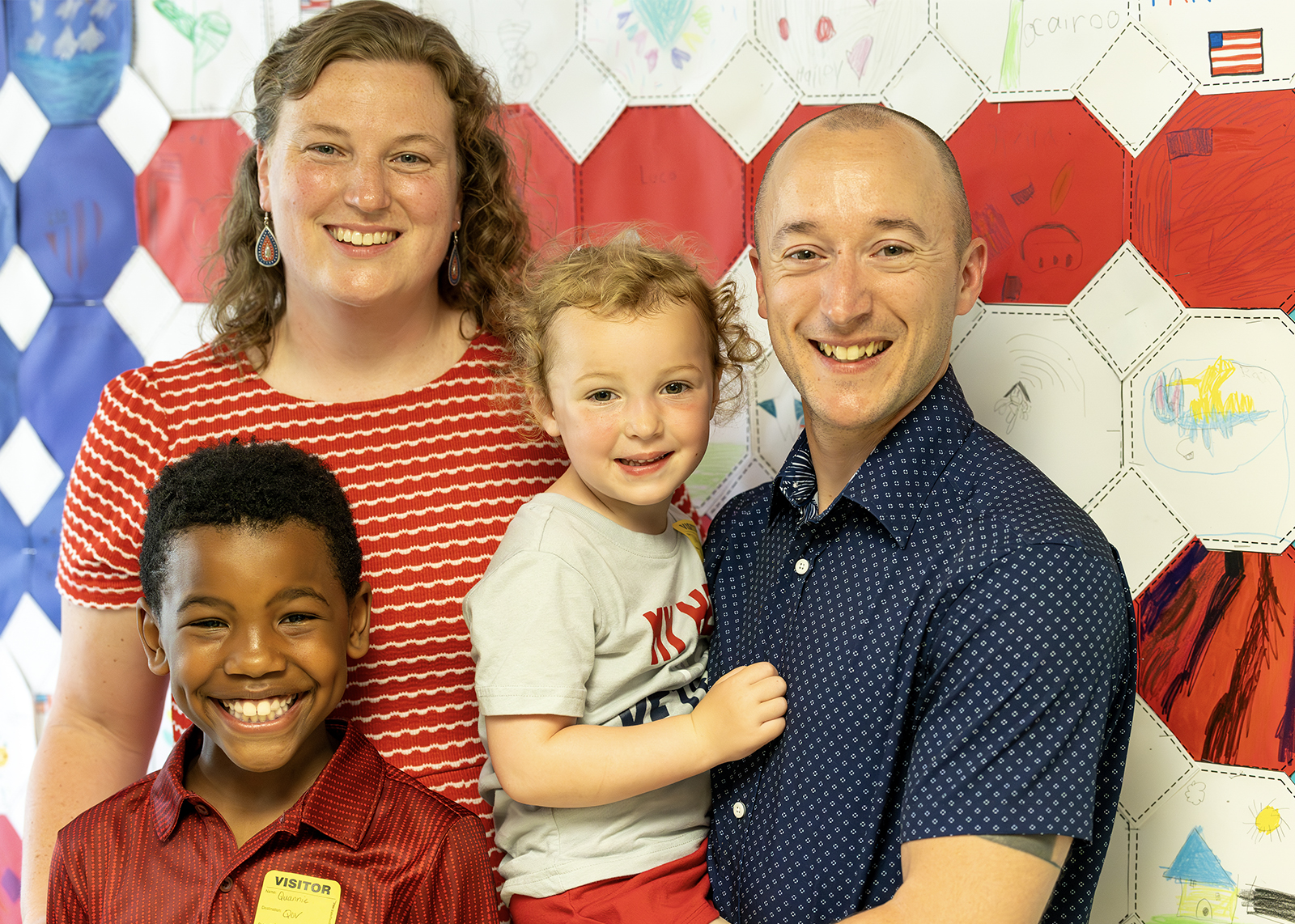 family with veteran smile at camera with american flag art in background