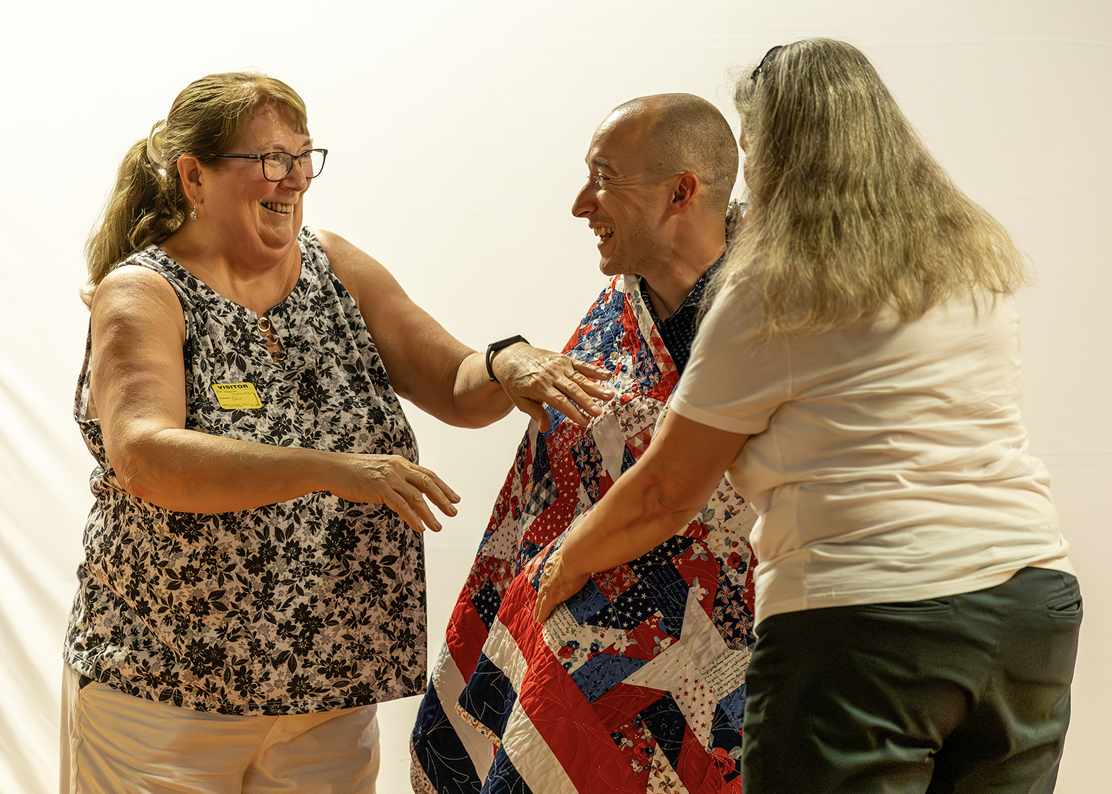 veteran is draped with handmade quilt on elementary school stage