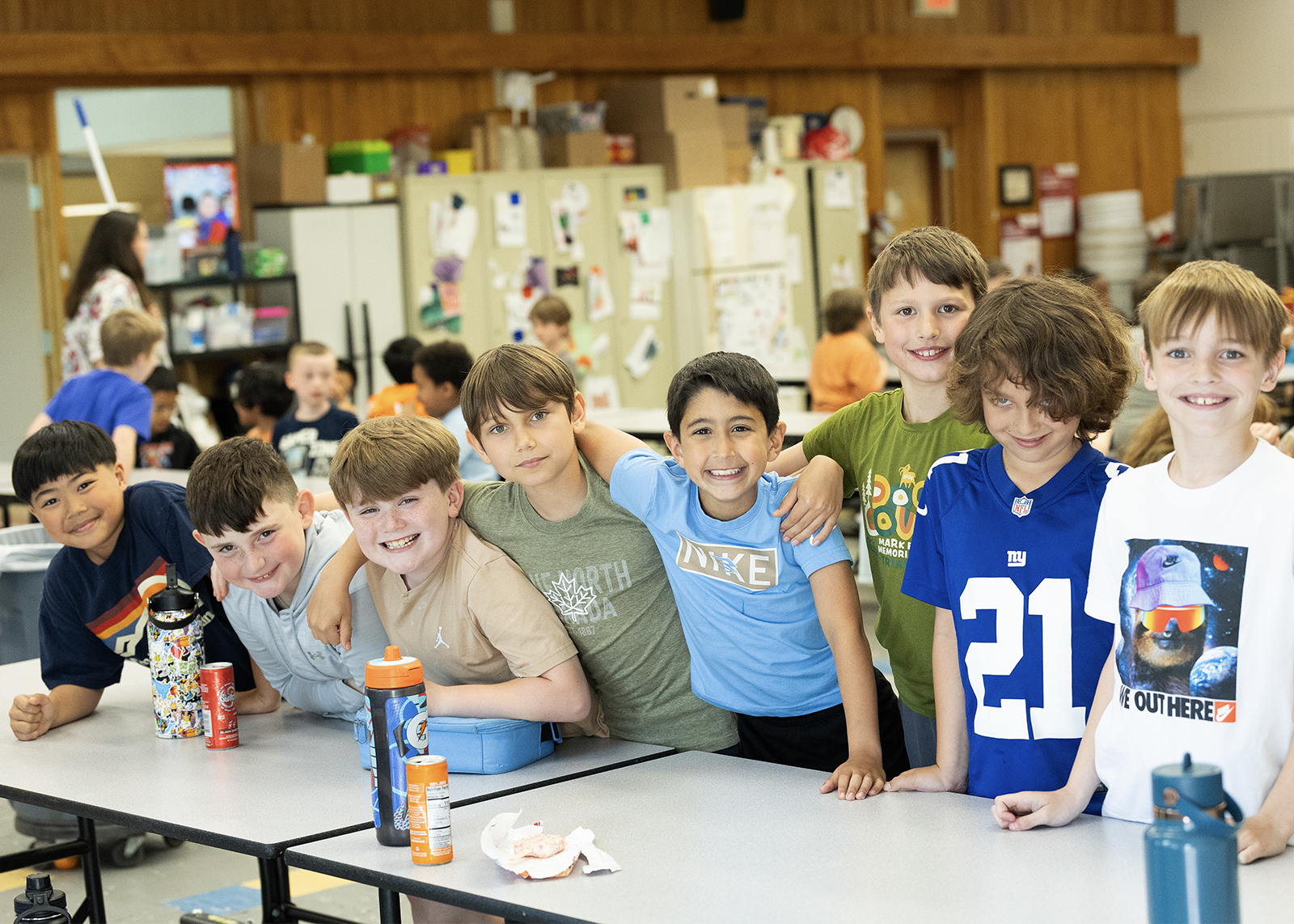 group of elementary students lined up at cafeteria table smiling