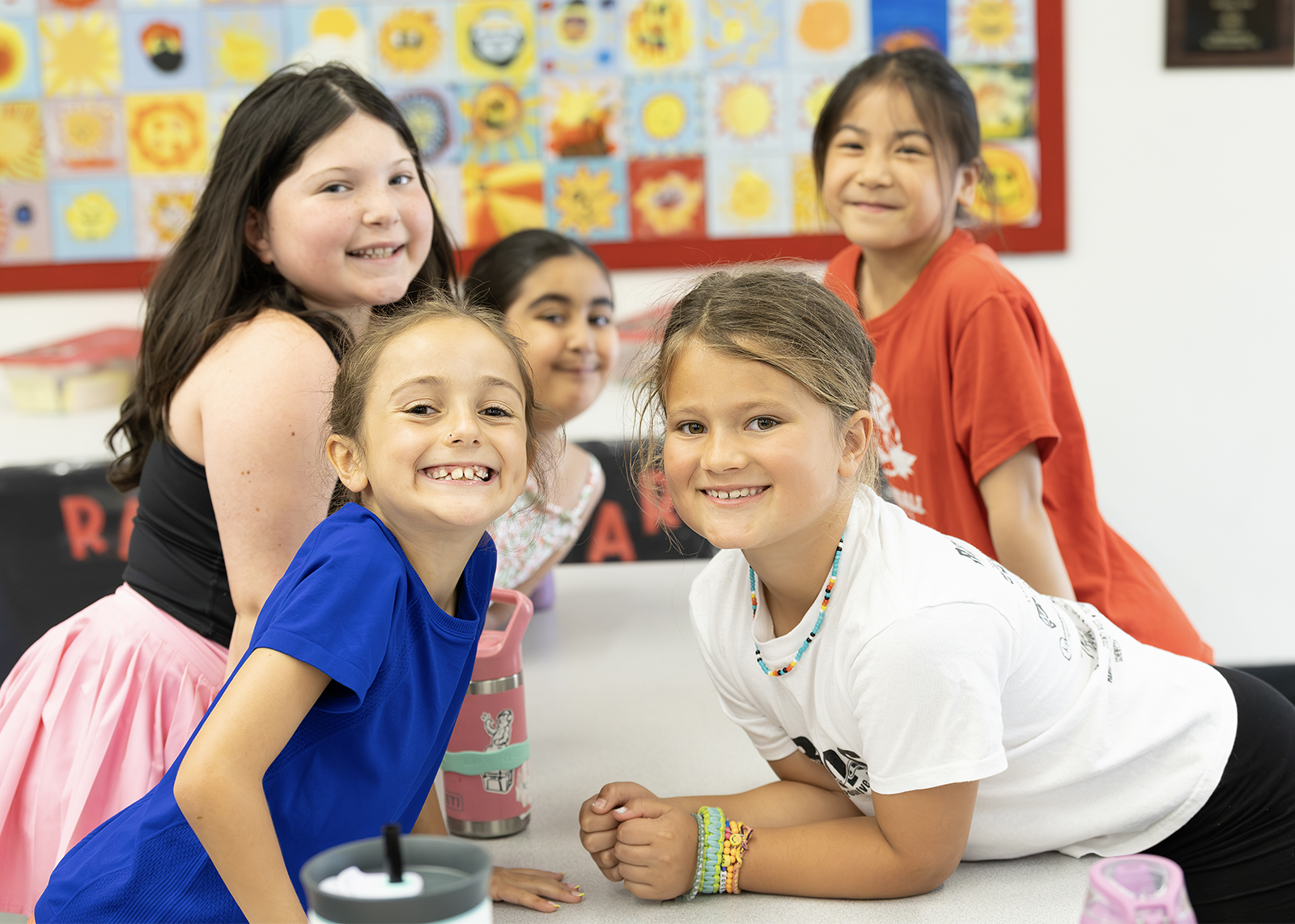 group of elementary students lined up at cafeteria table smiling