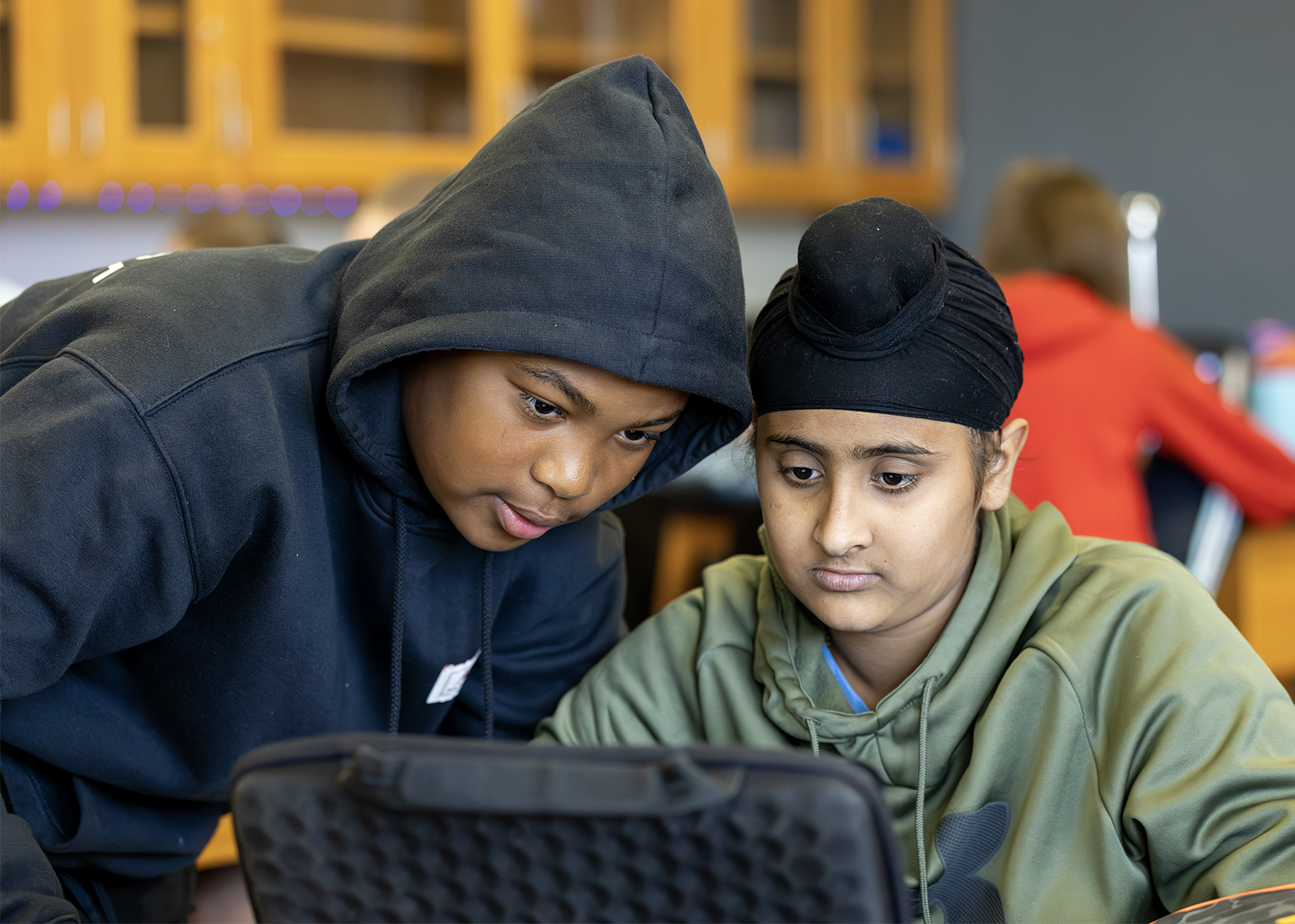 two middle schoolers looking at the same chromebook