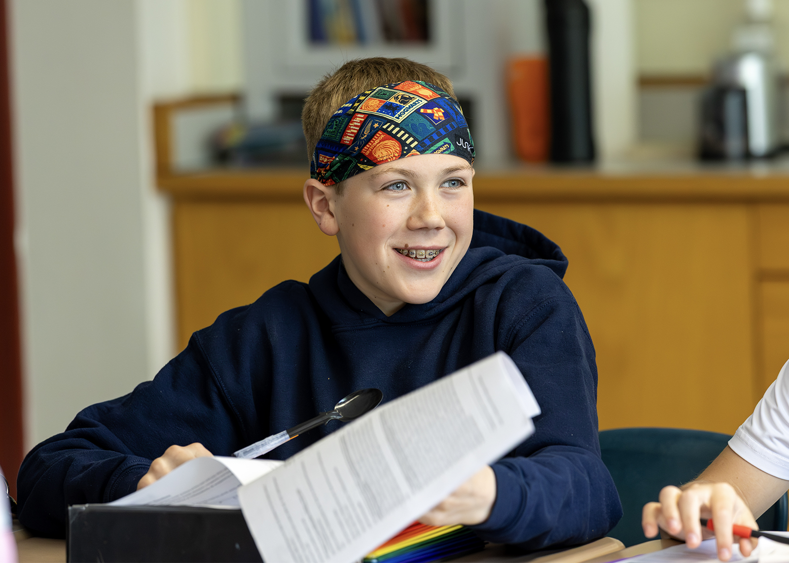 middle schooler smiling in class while wearing a headband