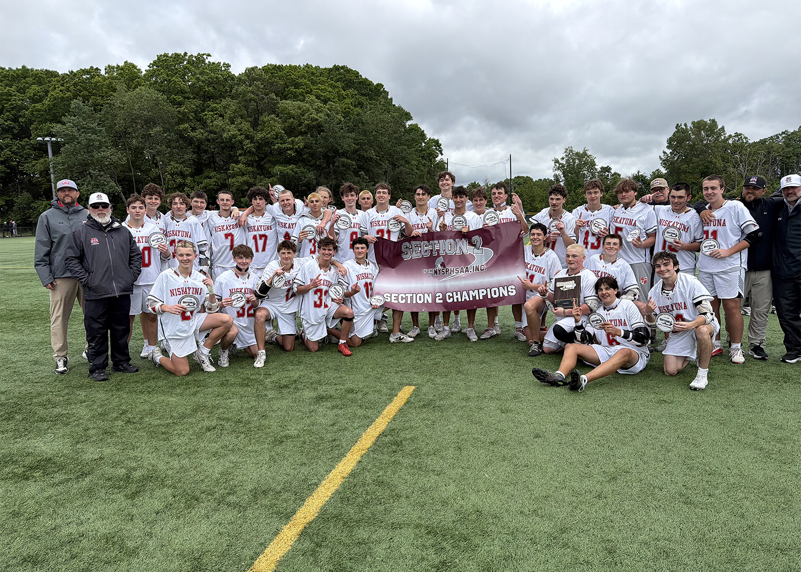 boys high school lacorsse team with sectional championship banner