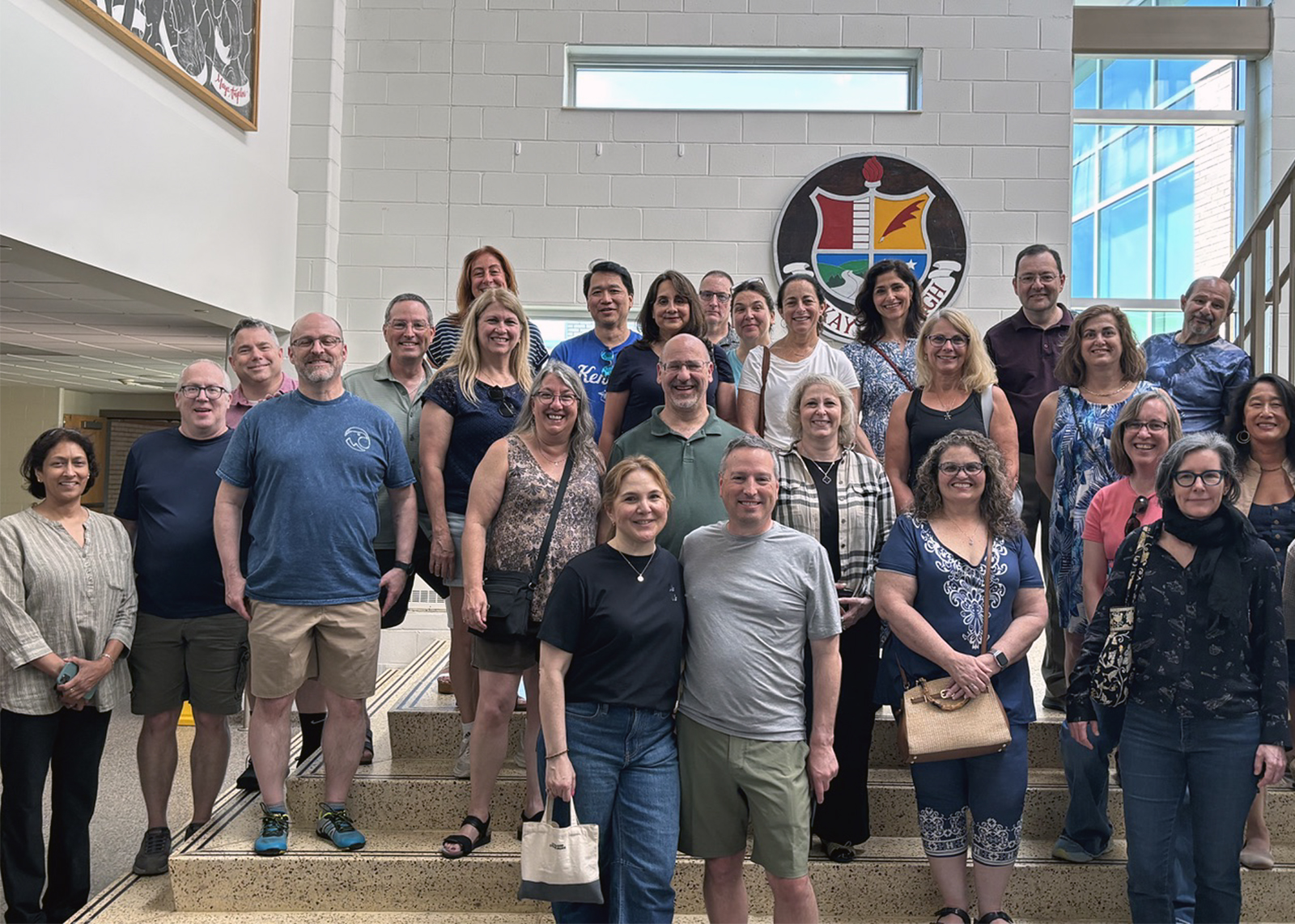 Members from the class of 1986 smile in a group picture in high school hallway
