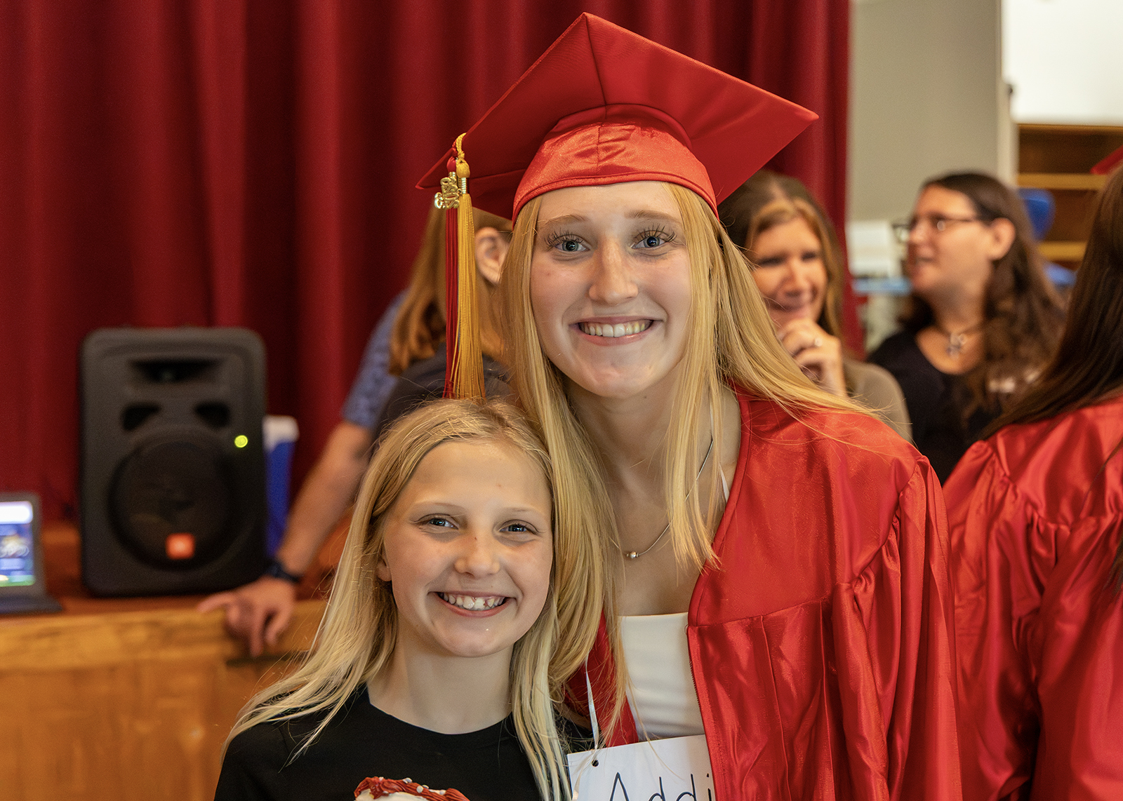 graduate in cap and gown at elementary school smiling with sbiling