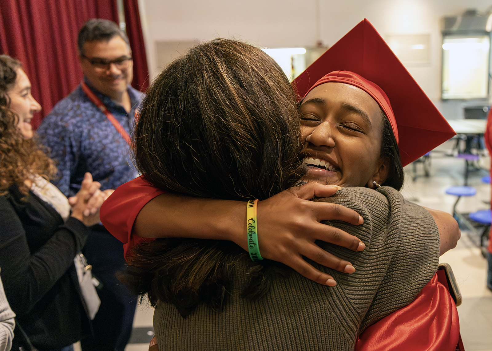 graduate in cap and gown hugs former teacher