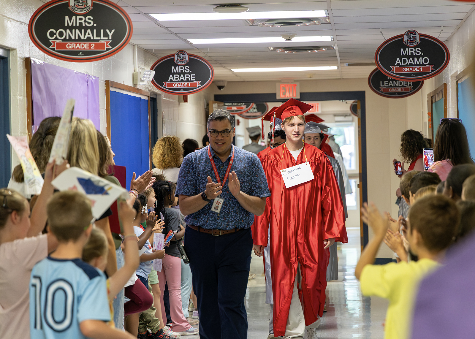 graduates walk down hall of elementary school