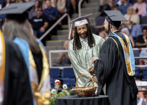graduate laughs on stage while shaking assistant principal's hand at ceremony