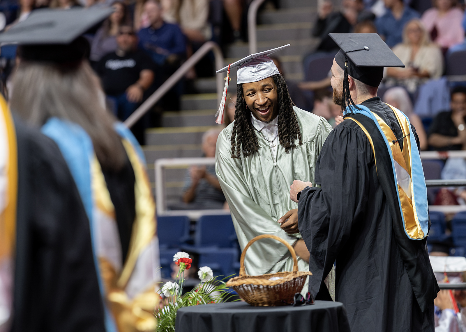 graduate laughs on stage while shaking assistant principal's hand at ceremony