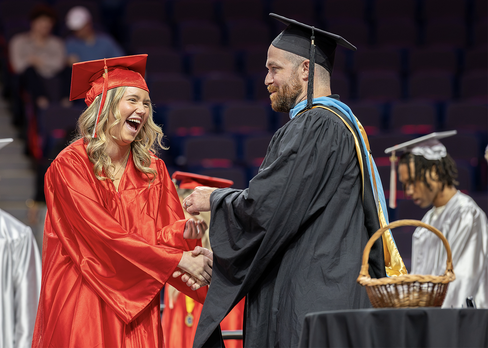 graduate laughs on stage while shaking assistant principal's hand at ceremony