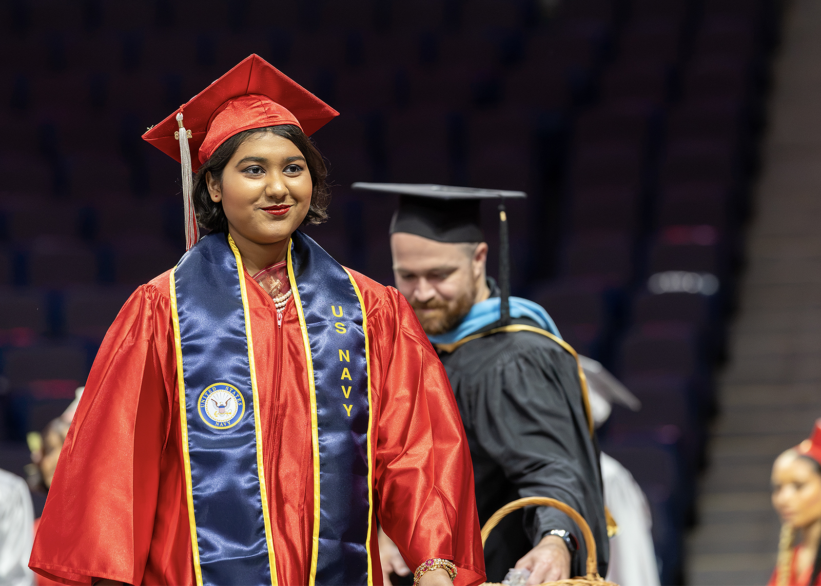 graduate wearing NAVY sash smiles on stage