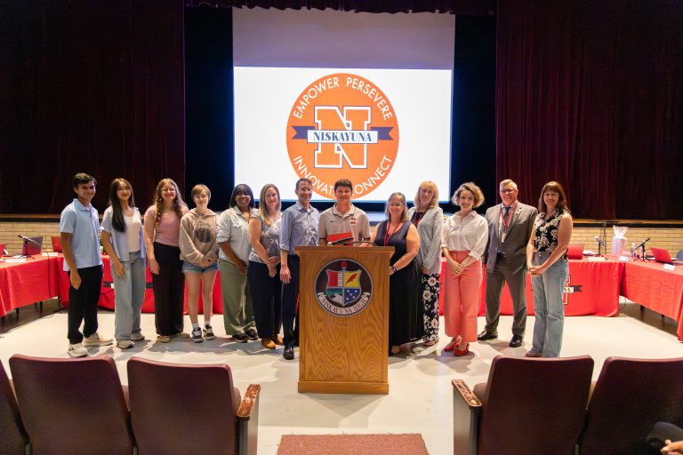 Boys lacrosse captain holds certificate with board of education members