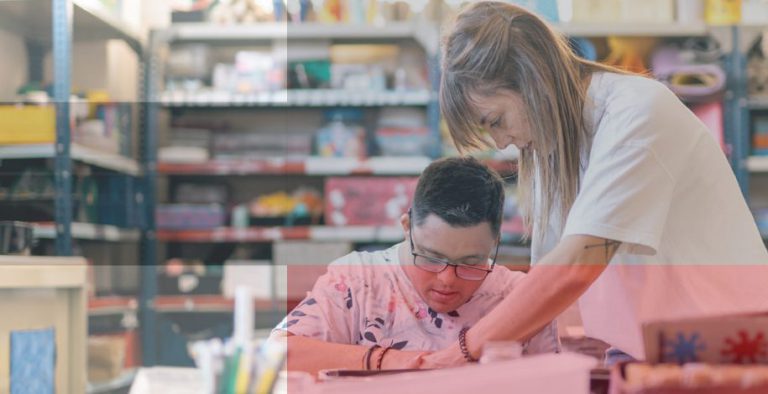 The teacher reaches over the desk to help a student
