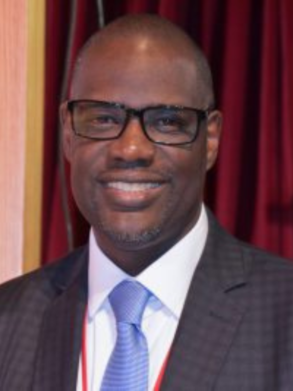 Professional photo of Timothy Fowler, smiling wearing a black suit with a blue tie