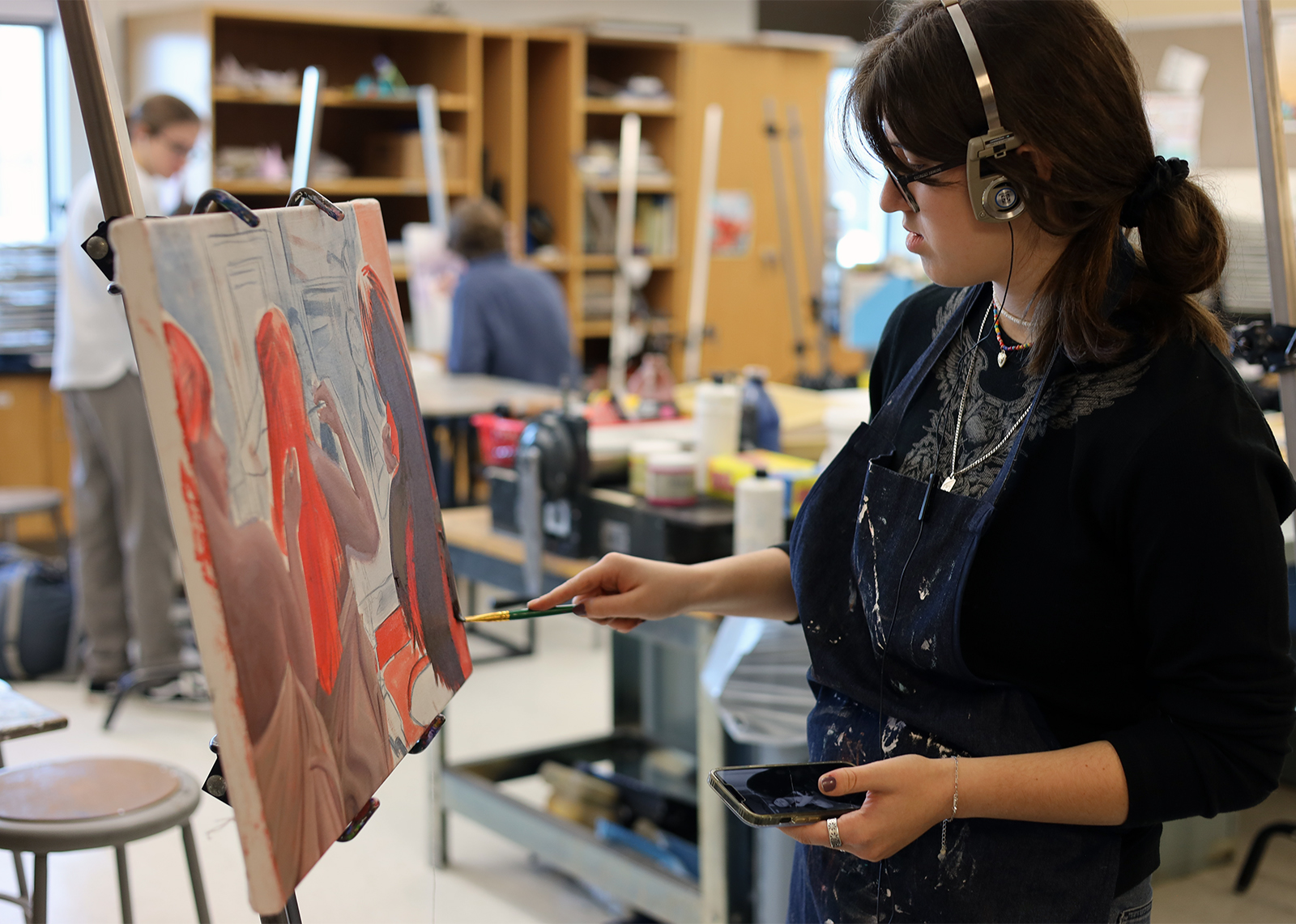 A high school art student painting on canvas.