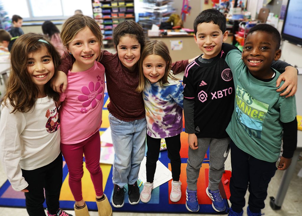 Several young children gathered in a classroom smiling.