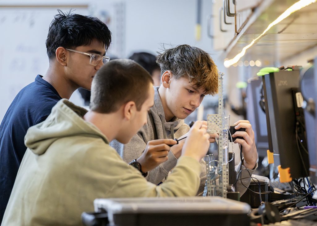 Three teens working on an engineering project.