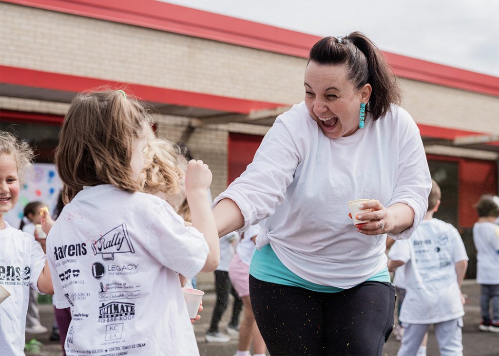 An educator happily interacting with a student outdoors.