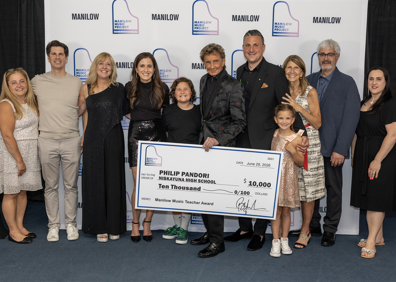 group photo of music educators and families holding a big check that reads phil pandori niskayuna highscholl $10,000 barry manilow music award