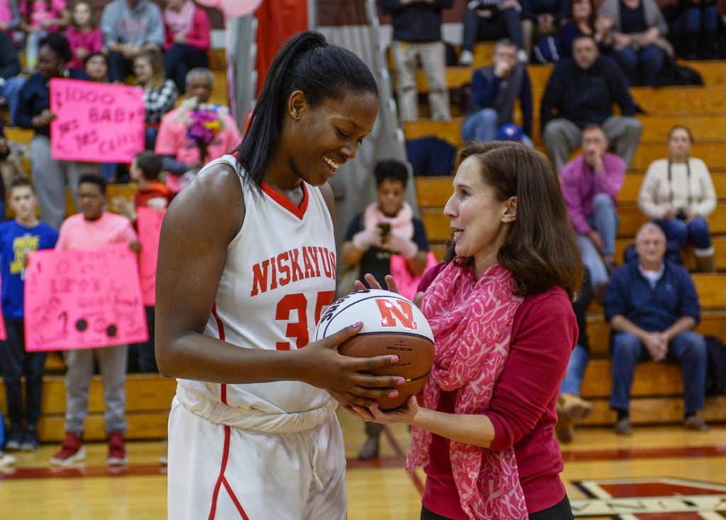 A coach and basketball player share a happy moment on the court.
