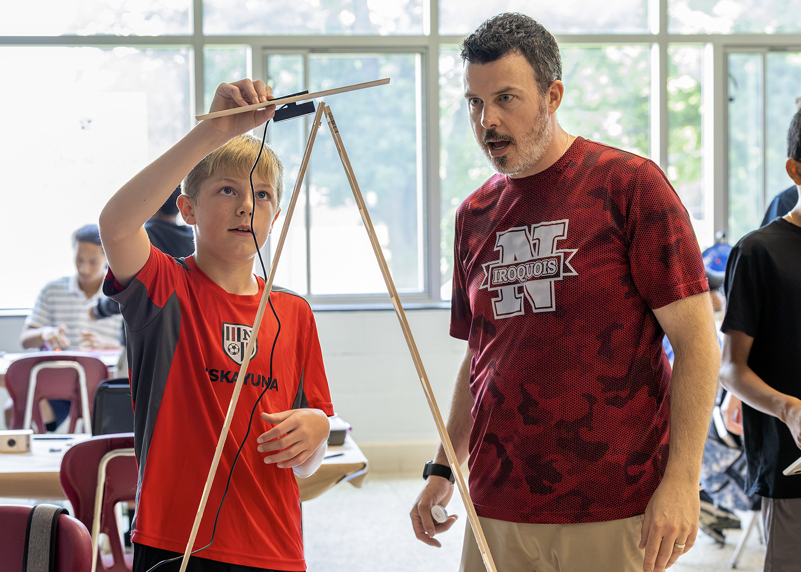 student and science teacher teasting a project with a wooden tower