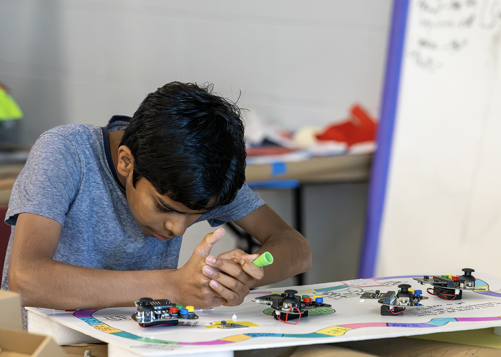 YMECSlider2 middle schooler focuses on gluing something to a project with game controllers