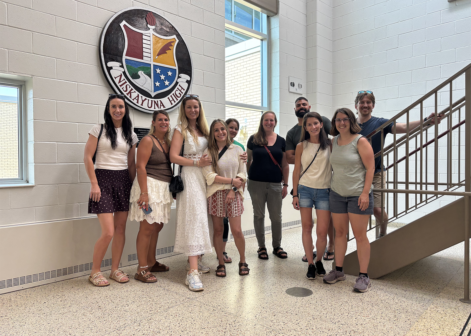 group of alumni in front of school crest