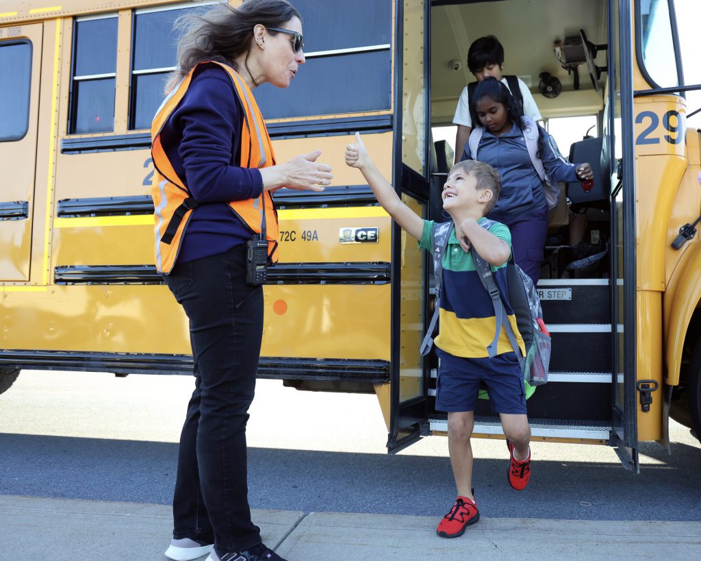 A child happily exiting a school bus at school.