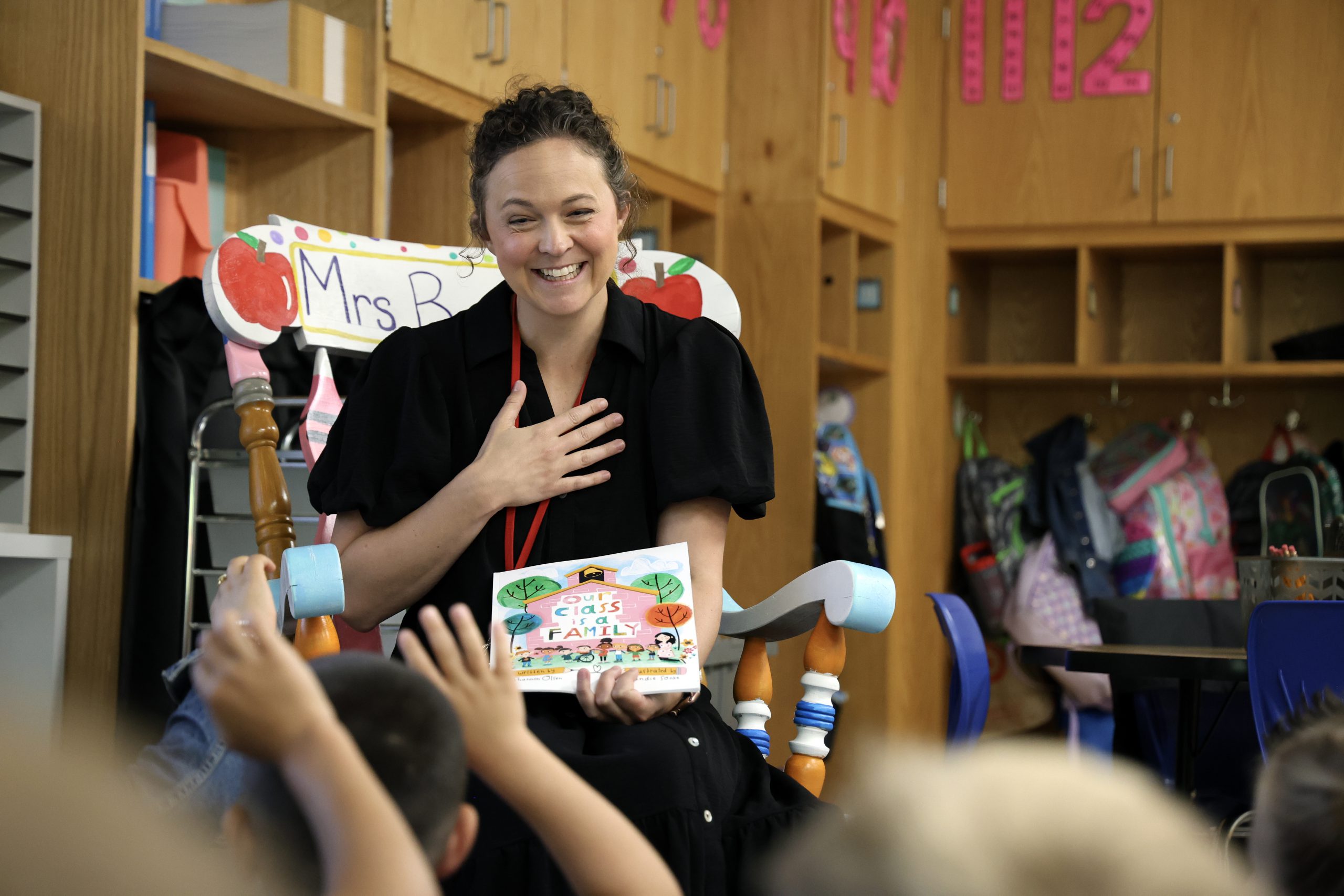 A teacher smiles cheerfully with students during a storytime.