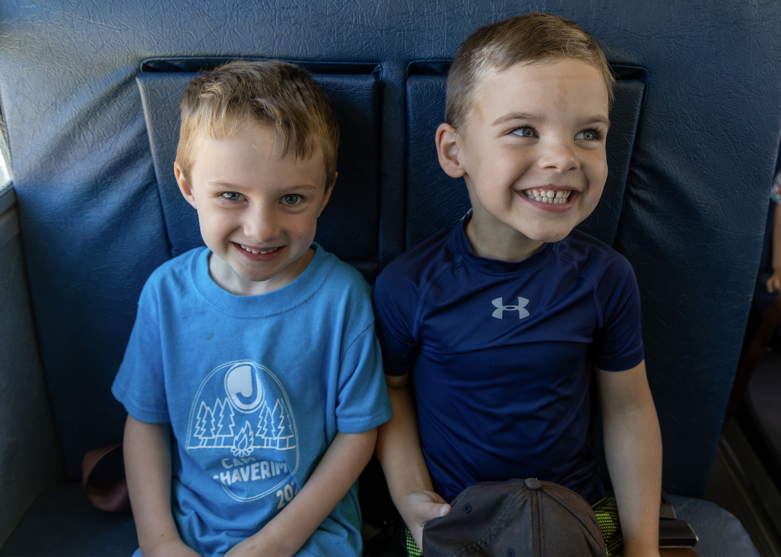 two kindergartners smile in front seat of school bus