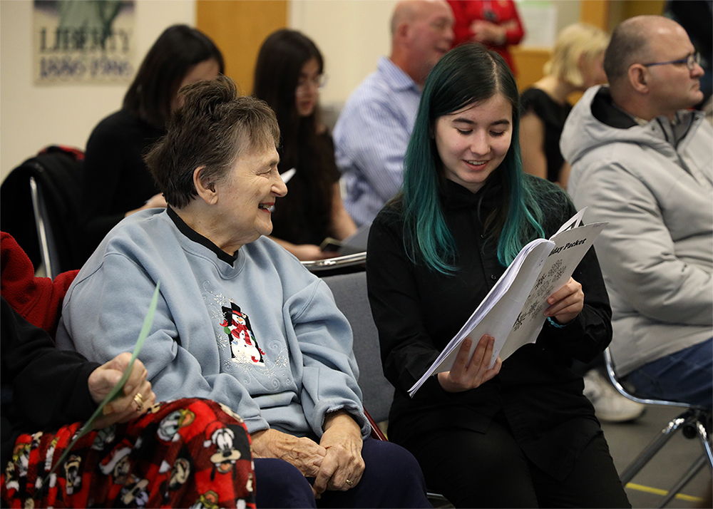 A student holding a program for an elderly community member.