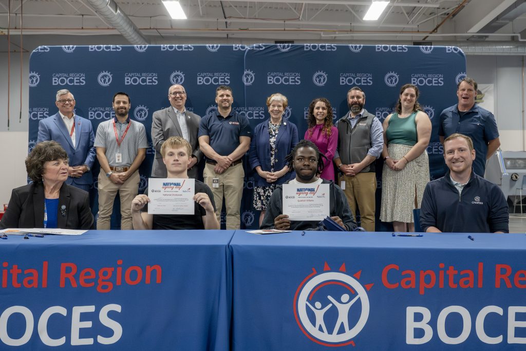 two students holding CTE signing day certificates at a a ceremony table