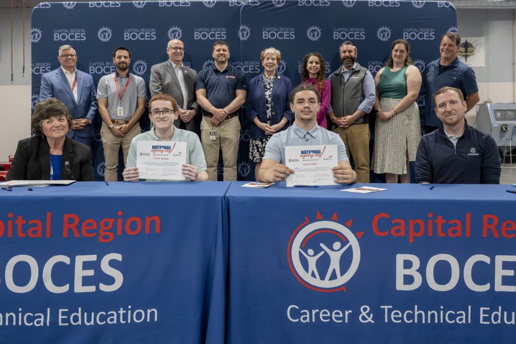 two students holding CTE signing day certificates at a a ceremony table