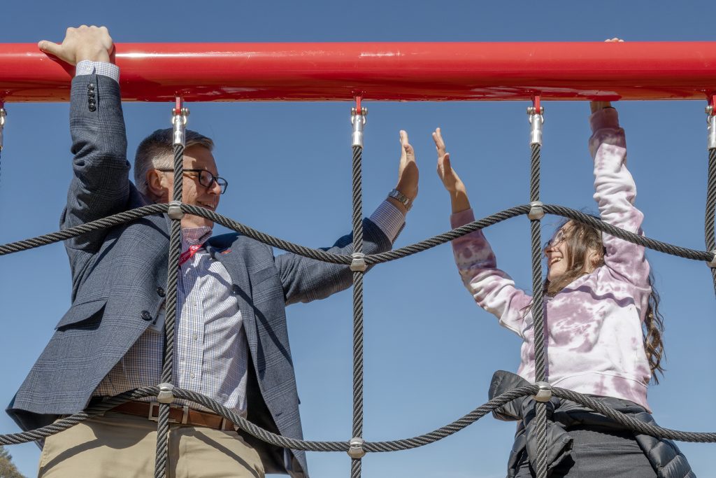 Superintendent Carl Mummenthey high fives a student on the playground.