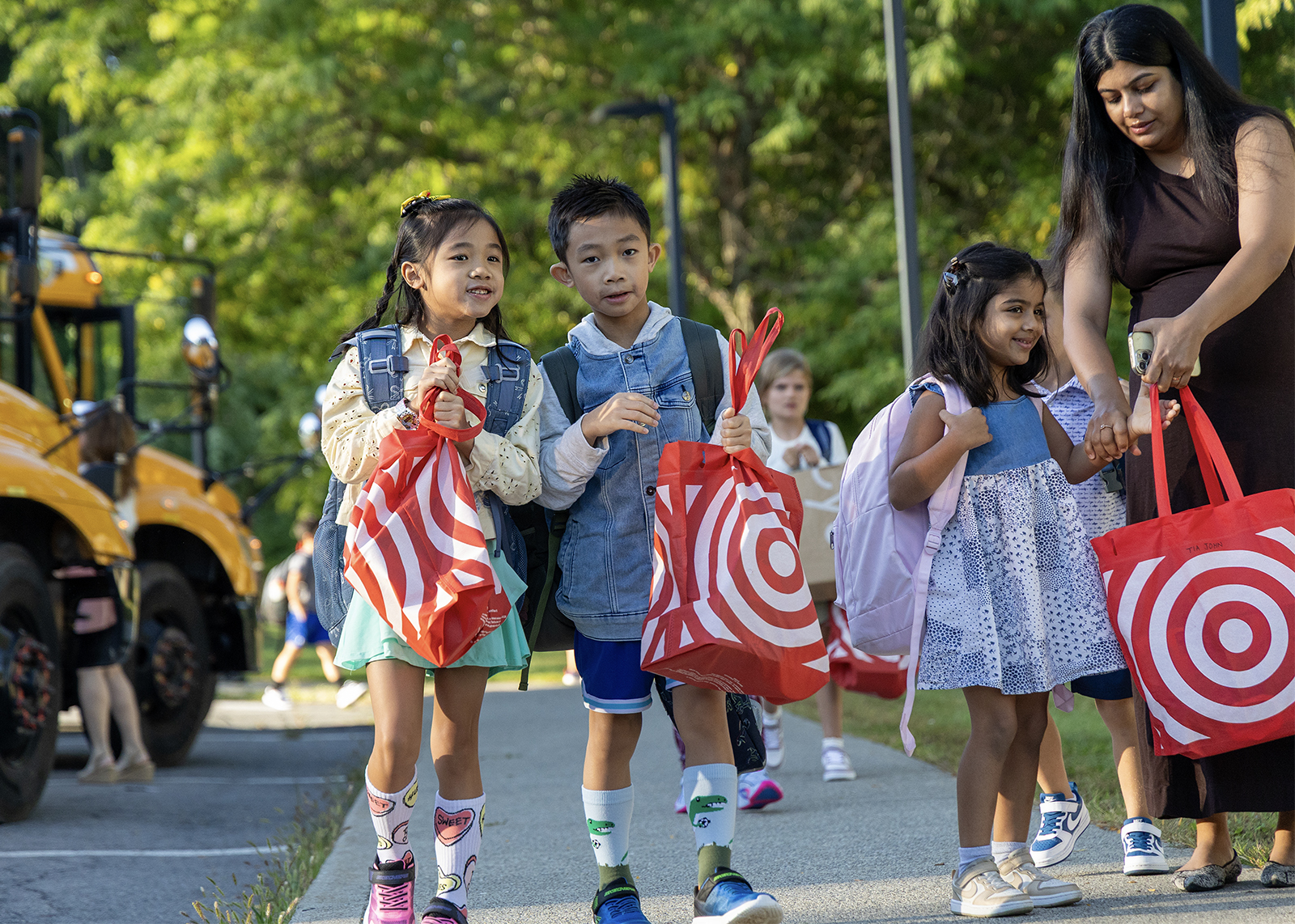 students with school supply bags walk in on first day of school