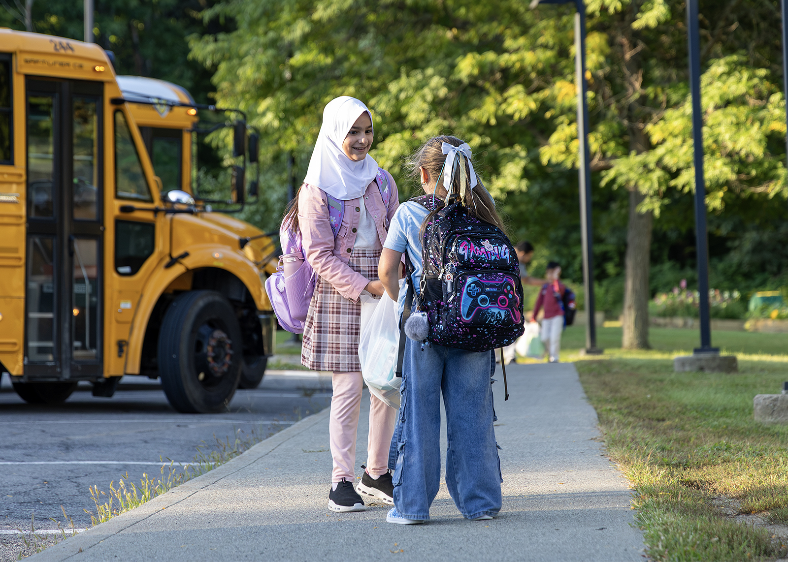 two students run to greet each other on the first day with buses in the background