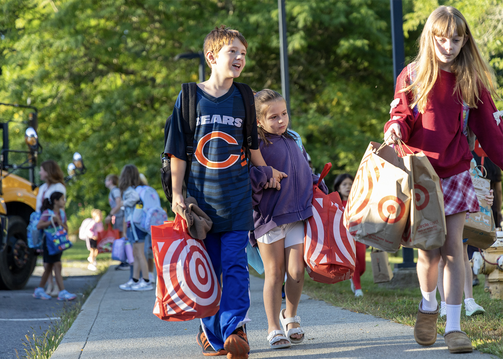 two students holding hands carrying supplies into school