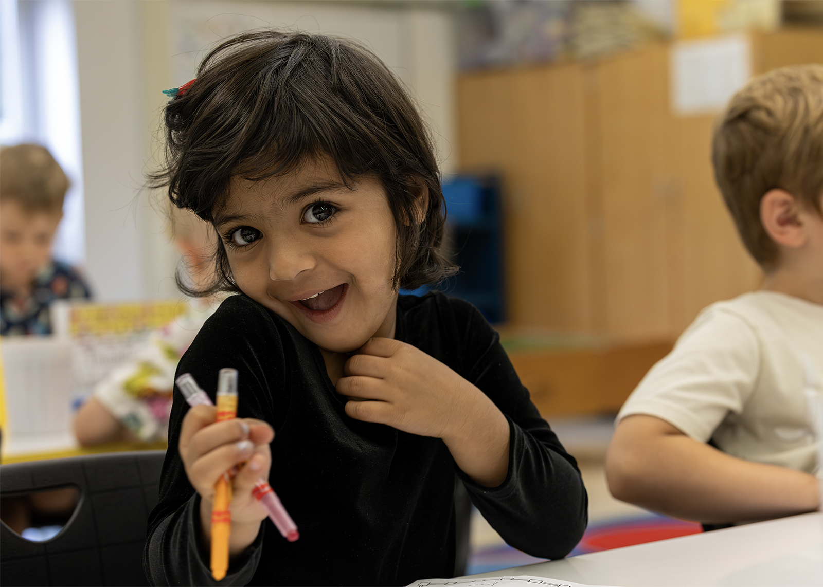 elementary student smiling holding crayons