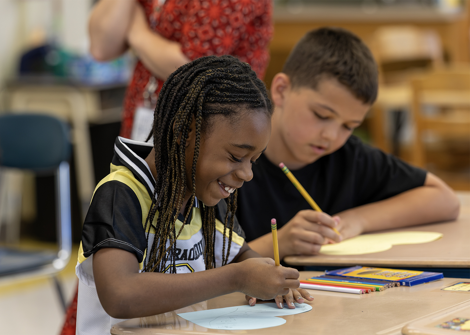 elementary student smiling while working on a project at a desk