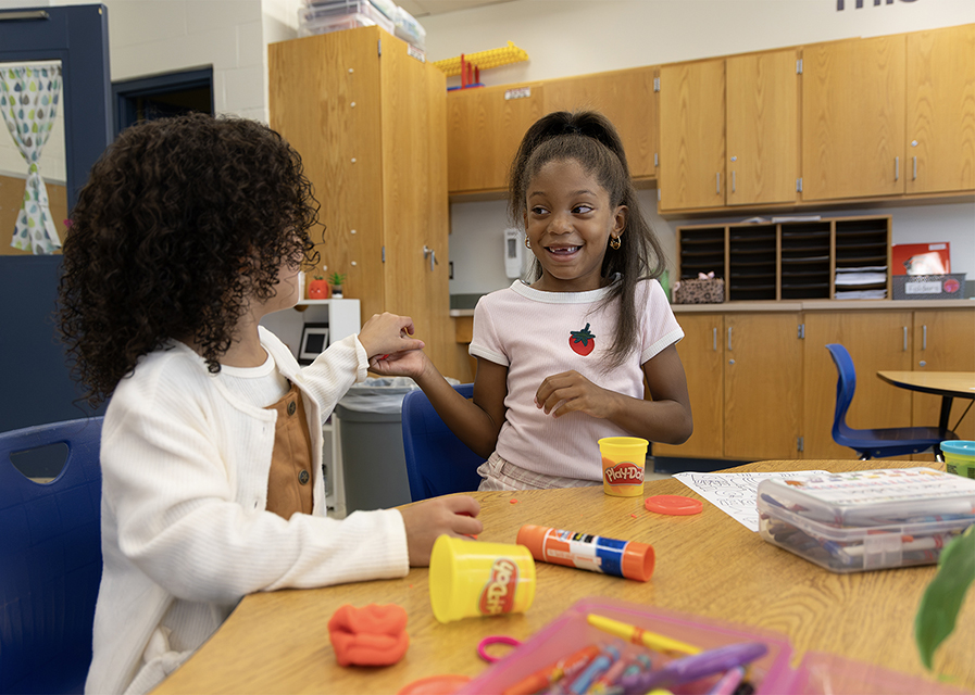 Two young students interacting in a classroom.