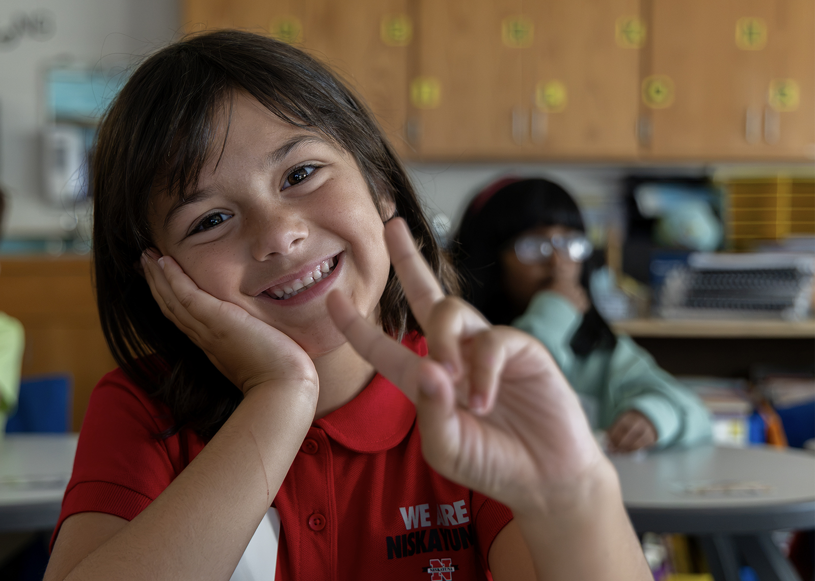 elementary student smiling and give peace to the camera
