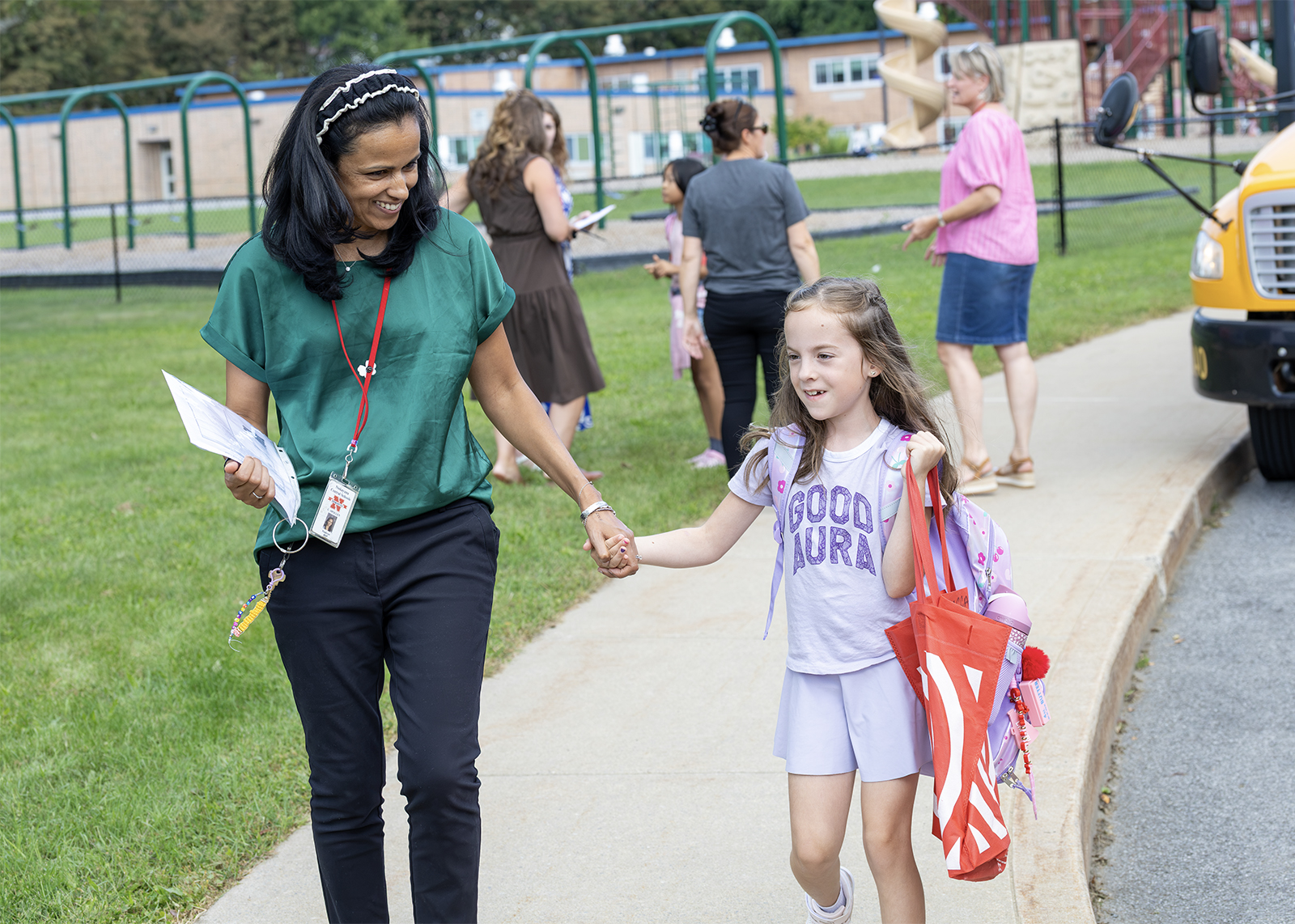 teacher walks elementary student to the bus