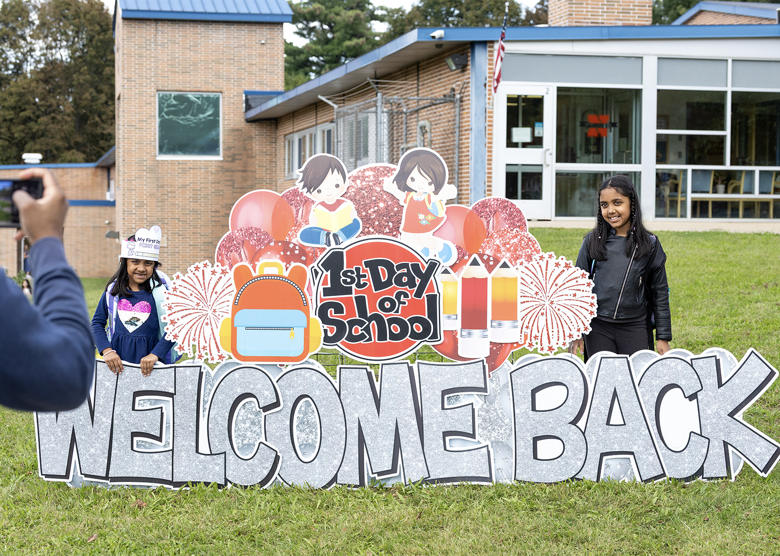 elementary students smile in front of a welcome back sign