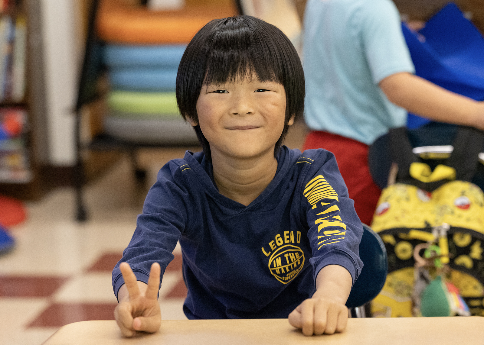 elementary student smiling and give a peace sign